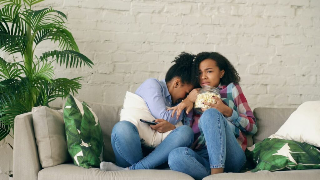 Two women watching TV and eating popcorn